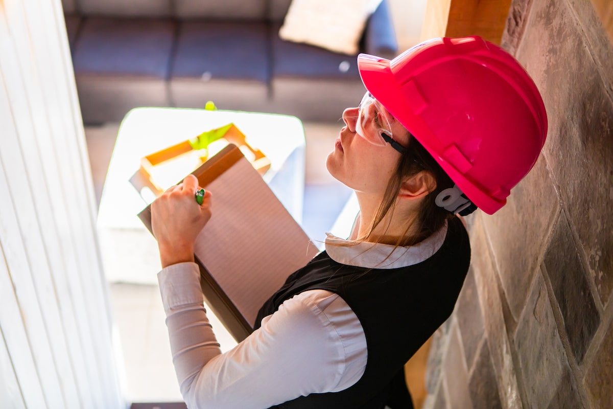Woman with helmet performing a mold inspection in a house.